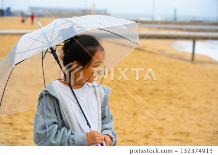 Asian girl in glasses with umbrella on the shore of the eastern sea Asian girl in glasses with umbrella on the shore of the eastern sea 132374913