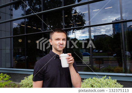 Caucasian office worker drinking coffee outside. White paper kraft disposable cup for coffee with white plastic lid. Take-away cup. 132375113