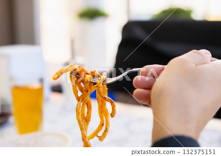 Lagman noodles on fork. man eats bucatini noodles. noodle with meat 132375151