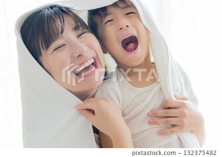 Mom wiping her child with a towel Mom wiping her child with a towel 132375482