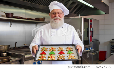 Santa Claus dressed as a chef holding a tray of gingerbread men cookies. Santa Claus dressed as a chef holding a tray of gingerbread men cookies. 132375709