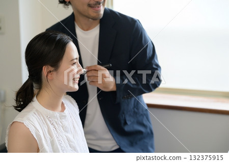 Man applying make-up to a woman Man applying make-up to a woman 132375915