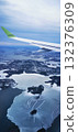 A view from the window of an airplane's wing and a snow-covered landscape with numerous bodies of water 132376309
