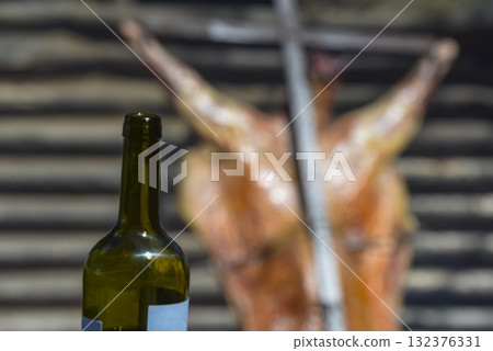 Bottle of wine with roast lamb in the background 132376331