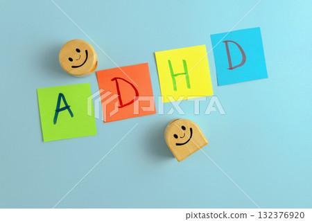 ADHD abbreviation on multi-colored paper and two wooden smileys. Attention Deficit Hyperactivity Disorder concept ADHD abbreviation on multi-colored paper and two wooden smileys. Attention Deficit Hyperactivity Disorder concept 132376920