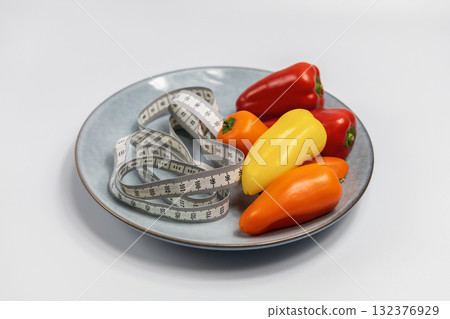 Plate with sweet peppers and a measuring tape. Concept of diet and weight loss 132376929