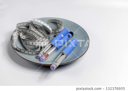 Ozempic Insulin injection pen for diabetics and weight loss on a plate with a measuring tape 132376935