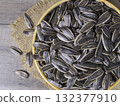 Striped sunflower seeds in a bowl on a wooden table. 132377910