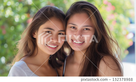 Close-up of twin sisters smiling directly at the camera, their resemblance and joy evident on a sunny day. Close-up of twin sisters smiling directly at the camera, their resemblance and joy evident on a sunny day. 132378988