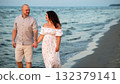 Couple enjoys a romantic evening stroll along the beach at sunset 132379141