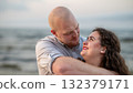 Couple enjoys a romantic moment by the beach during sunset while sharing smiles and affection 132379171
