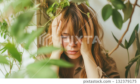 A woman appears overwhelmed or stressed, her hands on her head amidst a vibrant indoor jungle of potted plants. 132379175