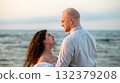 Couple enjoying a romantic moment at the beach during sunset with gentle waves in the background 132379208