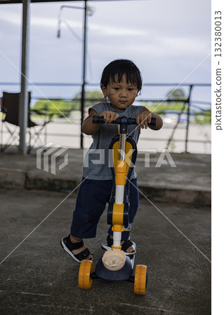 Photography of toddler determined while holding scooter, capturing energy and growth, suitable for parenting ads, lifestyle promotions, and childhood storytelling visuals. Photography of toddler determined while holding scooter, capturing energy and growth, suitable for parenting ads, lifestyle promotions, and childhood storytelling visuals. 132380013