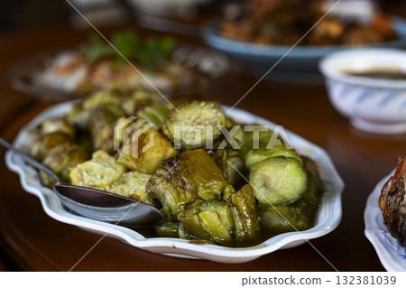 Grilled Eggplant On Party Table, A tender grilled eggplant sits on a lively party table, surrounded by vibrant appetizers, ideal for a culinary photo capture or a festive snack display. Grilled Eggplant On Party Table, A tender grilled eggplant sits on a lively party table, surrounded by vibrant appetizers, ideal for a culinary photo capture or a festive snack display. 132381039