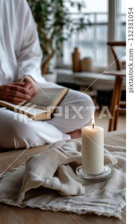 Peaceful indoor scene with a lit candle and a person reading in soft natural light Peaceful indoor scene with a lit candle and a person reading in soft natural light 132381054