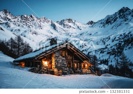 A charming chalet nestled in snow-covered mountains offers warmth and comfort. Mesmerizing twilight sets a peaceful atmosphere for a perfect winter getaway 132381331