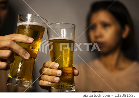 Celebration Toast With Cold Beer, Friends raise cold beer bottles in a toast, condensation dripping under festive lights, perfect for a cheerful photo or a party spirit showcase. 132381553