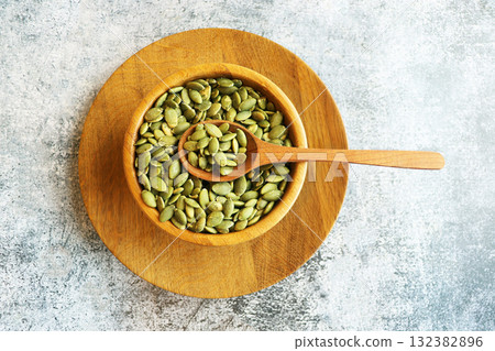 Bowl and spoon of peeled pumpkin seeds on grey marble table Bowl and spoon of peeled pumpkin seeds on grey marble table 132382896