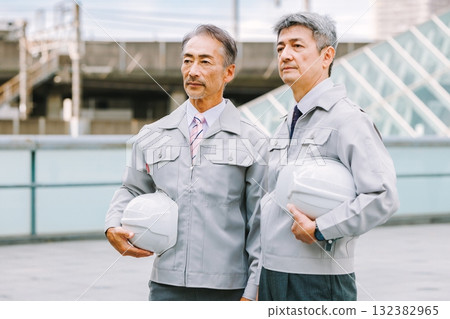 一個穿著工作服的人站在一個建築工地 132382965
