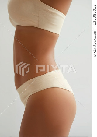 Close up side view of womans waist and hips wearing beige seamless underwear 132383012