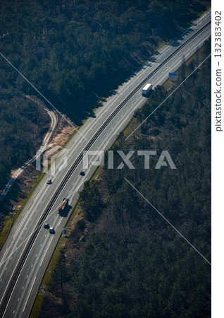 Highway view showing vehicles and lush forest in a remote area during daytime Highway view showing vehicles and lush forest in a remote area during daytime 132383402