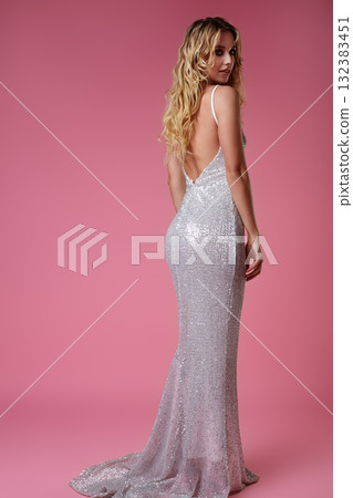 Elegant woman in pink sequin evening dress posing gracefully. Concept of fashion, femininity, luxury style and red carpet glamour. Perfect for clothing brands, style magazines and fashion campaigns 132383451