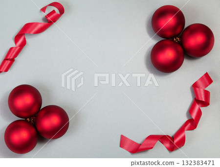 Top-down flat lay of red Christmas baubles and curled ribbon on neutral background, glossy ornaments and minimal styling creating festive holiday mood for seasonal campaigns. Xmas background Top-down flat lay of red Christmas baubles and curled ribbon on neutral background, glossy ornaments and minimal styling creating festive holiday mood for seasonal campaigns. Xmas background 132383471