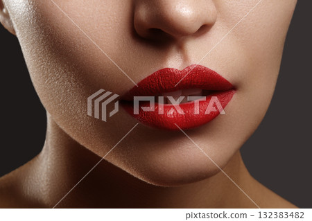 Studio close-up of a woman lower face with vivid red lipstick, soft lighting highlighting lip texture. Ideal for cosmetic ads, aesthetic surgery, cosmetology and beauty editorials 132383482