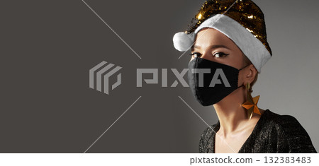 Woman with gold christmas hat, black medical mask. Fashion shiny style for xmas time. Protection from flu on holidays 132383483
