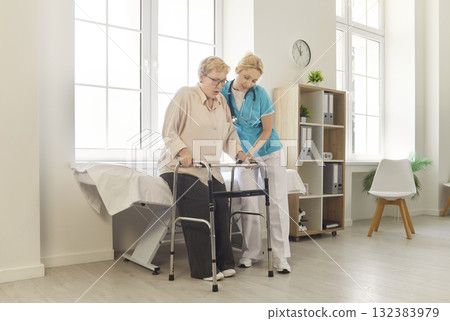 Nurse helping senior patient safe walking, using walker in medical clinic 132383979
