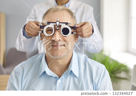 Optometrist or ophthalmologist uses special equipment to test vision of mature patient Optometrist or ophthalmologist uses special equipment to test vision of mature patient 132384027