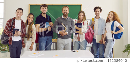 Photo of classmates and teacher standing against green chalk board on background. Photo of classmates and teacher standing against green chalk board on background. 132384040