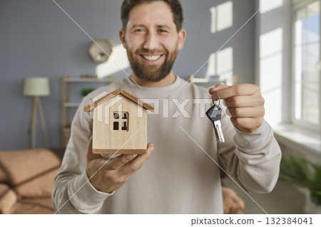 Smiling young man demonstrating house and bunch of keys 132384041