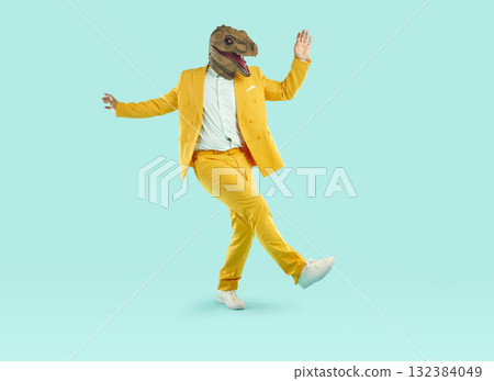 Energetic young man dancing wearing dinosaur head mask 132384049