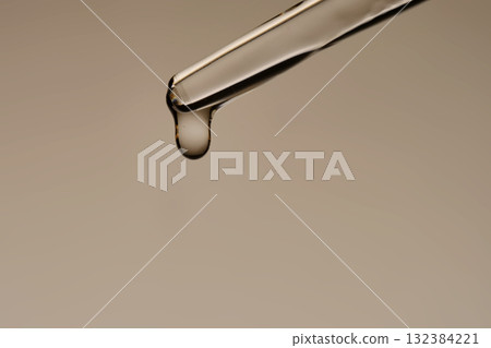 The texture of the serum flowing out of the pipette on a beige background. 132384221