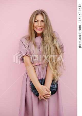 Smiling Woman In Pink Dress Holding Black Handbag 132384618