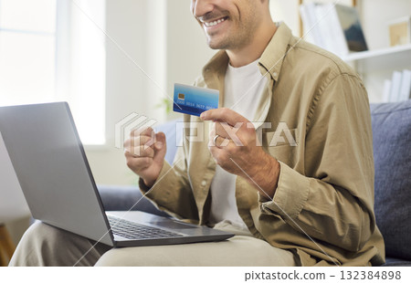 Happy man with credit card near laptop celebrating successful online payment 132384898