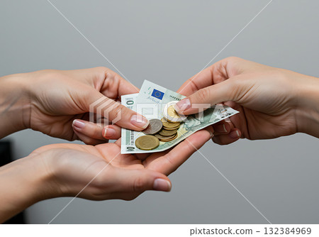 Close-up of hands exchanging euro cash and coins. A woman makes a payment to another person during a financial transaction Close-up of hands exchanging euro cash and coins. A woman makes a payment to another person during a financial transaction 132384969