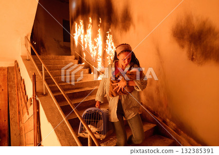 Woman escaping fire with baby and pet, running down stairs in smoke-filled building, emergency evacuation, rescue from burning building, dramatic scene, danger, motherhood. Woman escaping fire with baby and pet, running down stairs in smoke-filled building, emergency evacuation, rescue from burning building, dramatic scene, danger, motherhood. 132385391