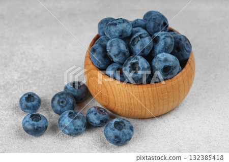 Fresh ripe blueberries in wooden bowl on light gray stone background closeup macro healthy food Fresh ripe blueberries in wooden bowl on light gray stone background closeup macro healthy food 132385418