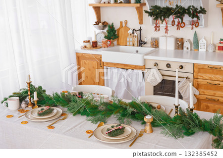 Elegant Christmas holiday table setting with greenery and simple decor on cozy kitchen background 132385452