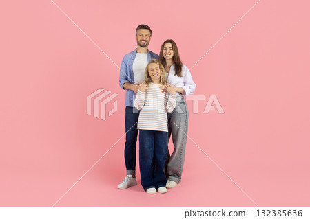 Portrait of happy young family smiling together in studio, pink background 132385636