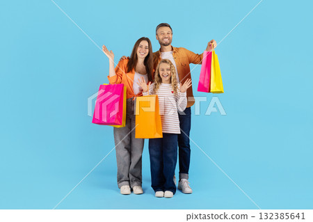 Cheerful family posing with colorful shopping bags in studio on blue background Cheerful family posing with colorful shopping bags in studio on blue background 132385641