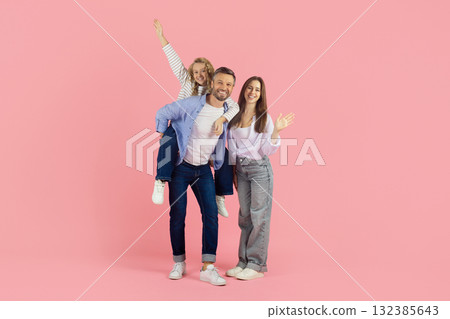 Family having fun on pink studio background. Daughter sitting on fathers back Family having fun on pink studio background. Daughter sitting on fathers back 132385643