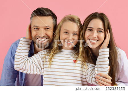 Happy family of three smiling in studio, daughter touching parents faces playfully 132385655