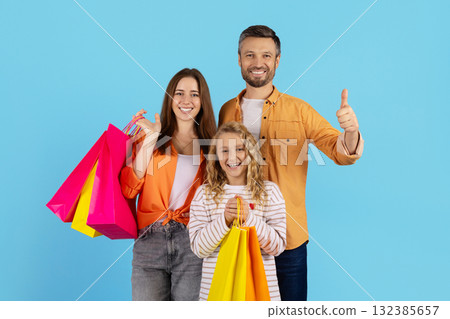 Smiling family showing shopping bags, standing close together and showing thumb up 132385657