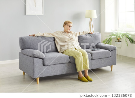 Senior mature relaxed woman sitting on comfortable sofa at home and sleeping enjoying having a rest Senior mature relaxed woman sitting on comfortable sofa at home and sleeping enjoying having a rest 132386078