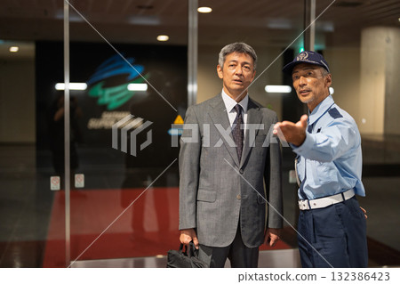 Security guard and businessman talking in front of a building 132386423