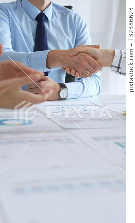 Business people shaking hands in office with financial charts, laptop and reports on table, symbolizing success, teamwork, agreement and corporate growth Business people shaking hands in office with financial charts, laptop and reports on table, symbolizing success, teamwork, agreement and corporate growth 132386623